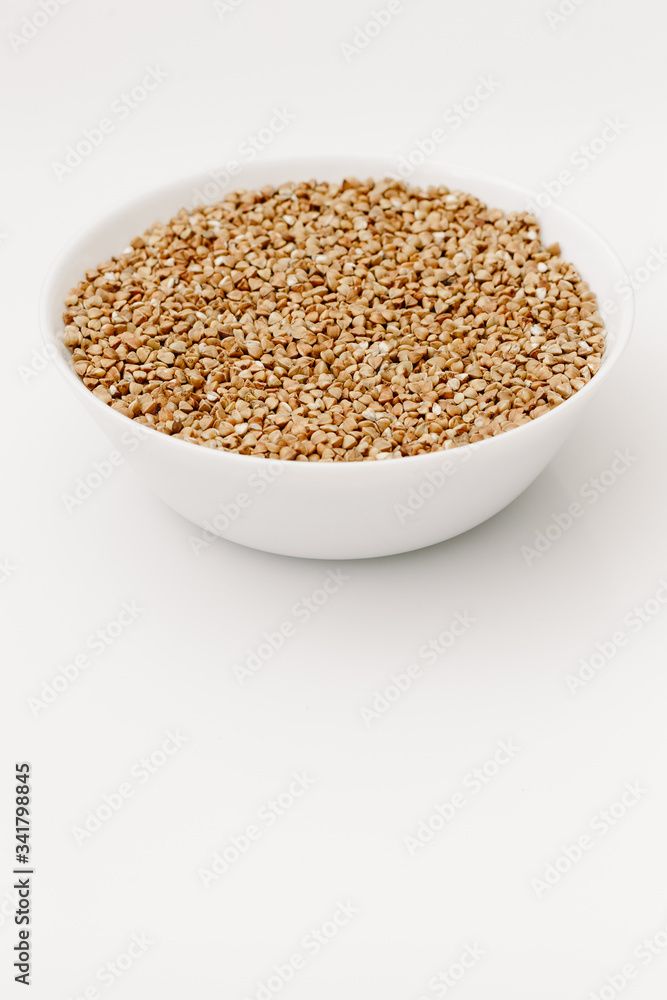 Bowl of uncooked buckwheat grains on white isolated background Bowl of uncooked buckwheat grains on white isolated background