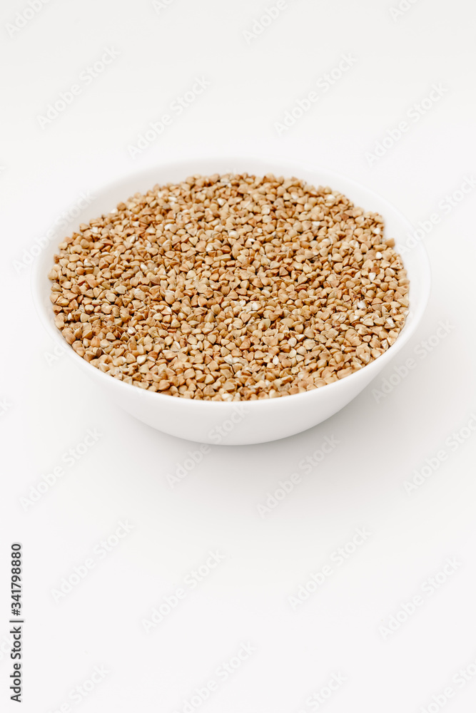 Bowl of uncooked buckwheat grains on white isolated background Bowl of uncooked buckwheat grains on white isolated background