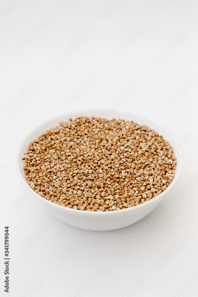 Bowl of uncooked buckwheat grains on white isolated background Bowl of uncooked buckwheat grains on white isolated background