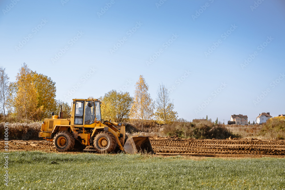 large yellow wheel loader aligns a piece of land for a new building. Preparation of the land for the auction. Leveling the landscape and adding sand for construction. large yellow wheel loader aligns a piece of land for a new building. Preparation of the land for the auction. Leveling the landscape and adding sand for construction.