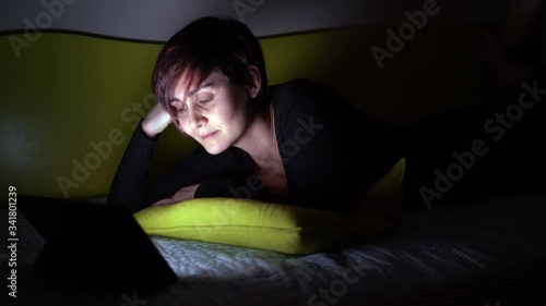 Young woman watching a nice film in bed at night. People hooked up with entertainment devices before going to bed. technology and leisure concept. Lifestyle at home for young people.