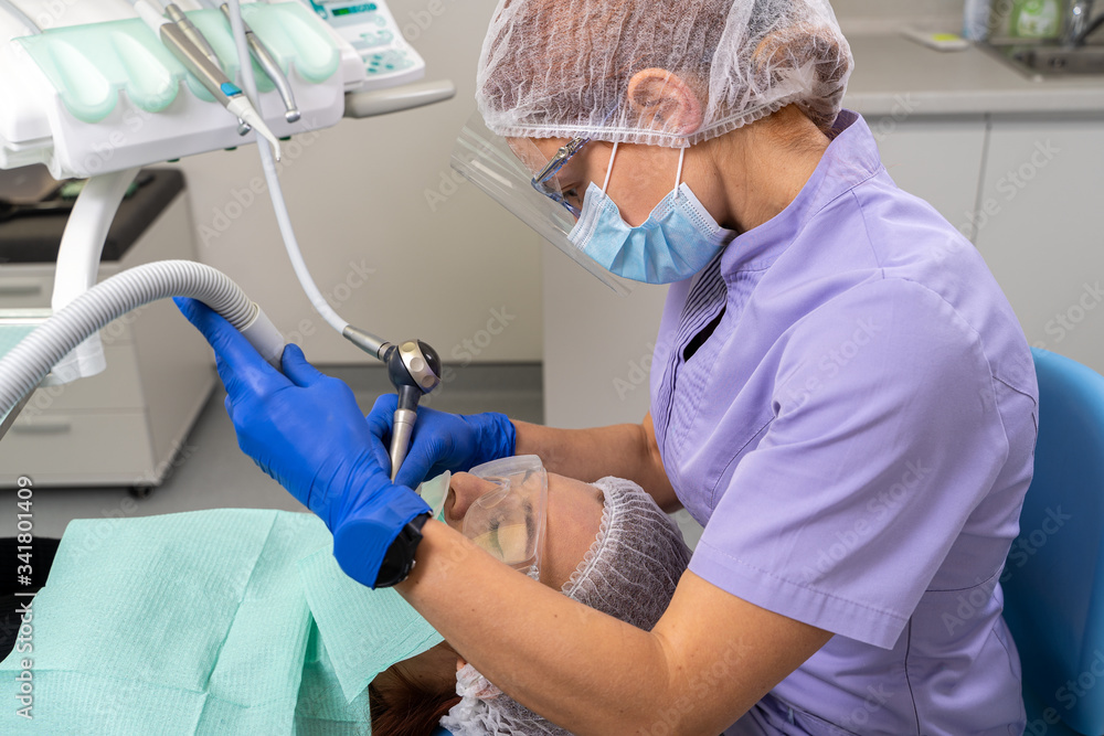 The dentist with the help of specialized tools provides treatment of the oral cavity to the girl patient. The dentist with the help of specialized tools provides treatment of the oral cavity to the girl patient.