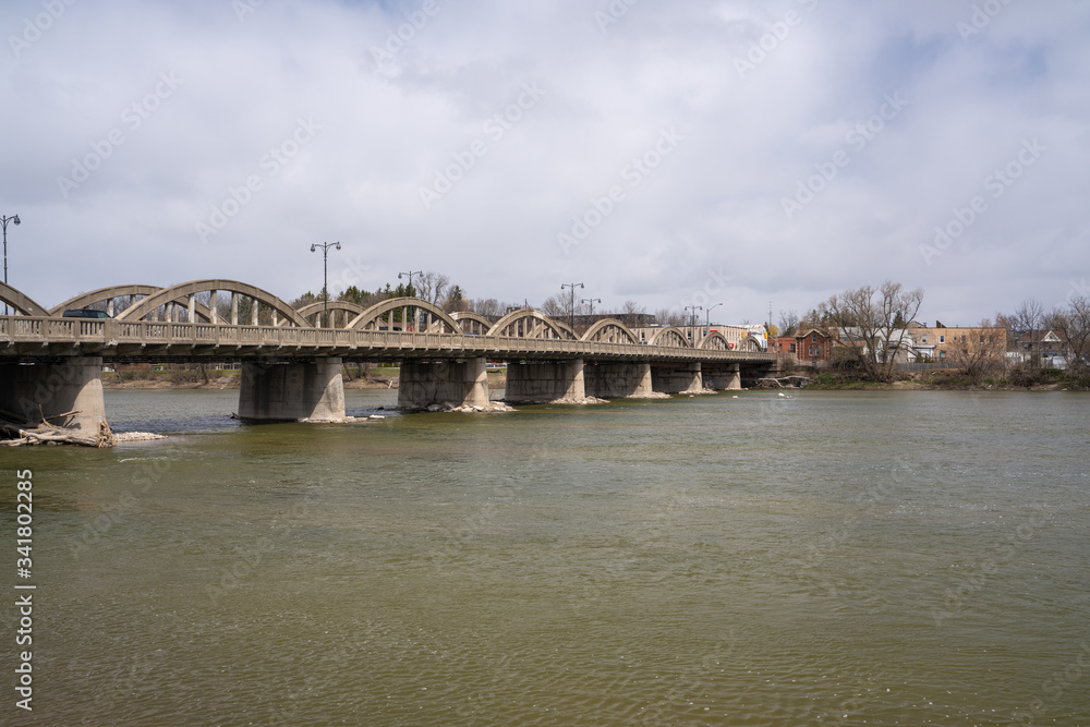 Image of an old bridge over the river with cloudy skies in spring 