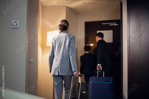 A family in formal wear leaving a hotel room with their suitcases