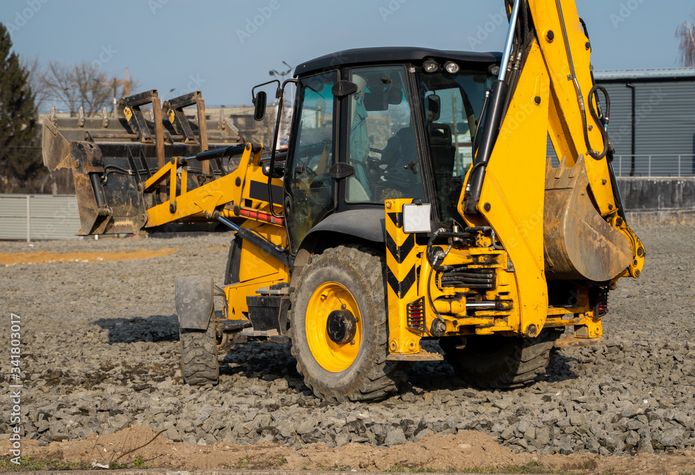 Yellow wheel loader Excavator machine working at construction site with a sand and gravel. Preparing of the fundament for a asphalting. Road construction site. Building of a parking. Yellow wheel loader Excavator machine working at construction site with a sand and gravel. Preparing of the fundament for a asphalting. Road construction site. Building of a parking.