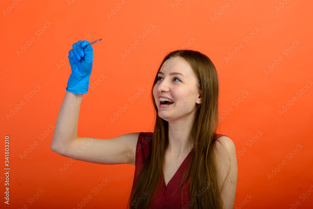 Girl in protective medical mask and blue gloves on red background. close-up portrait of a woman in a transparent mask. way to protect against coronavirus. Covid-2019, Pandemic 2020 Girl in protective medical mask and blue gloves on red background. close-up portrait of a woman in a transparent mask. way to protect against coronavirus. Covid-2019, Pandemic 2020