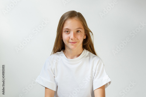 Pretty smiling joyfully girl with fair hair  dressed casually  looking with satisfaction at camera  being happy. Studio shot of good-looking beautiful teenager isolated against blank studio wall.