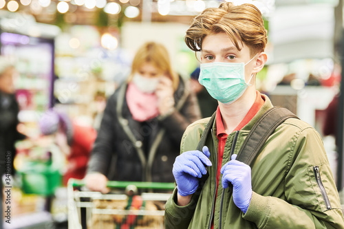 man in mask and protective gloves buying in shop at coronavirus epidemic