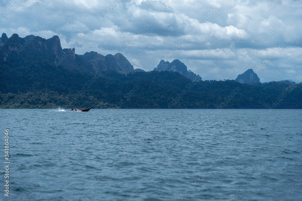 A boat rides on Lake Cheo Lan in Thailand. lake and mountain landscape.