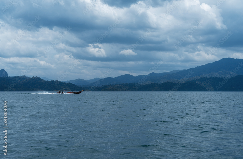 A boat rides on Lake Cheo Lan in Thailand. lake and mountain landscape.