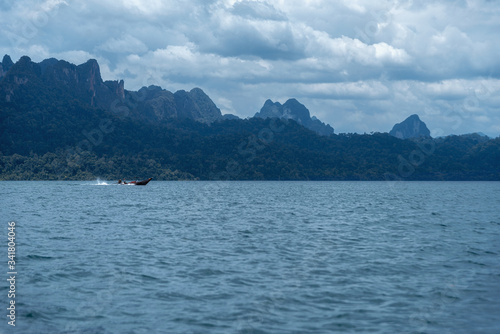 A boat rides on Lake Cheo Lan in Thailand. lake and mountain landscape. © mazurevanasta