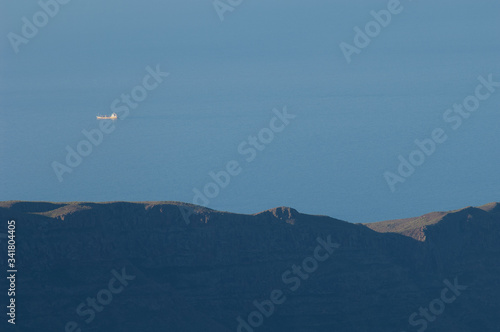 Boat sailing and cliff of the Mogan ravine. Mogan. Gran Canaria. Canary Islands. Spain.