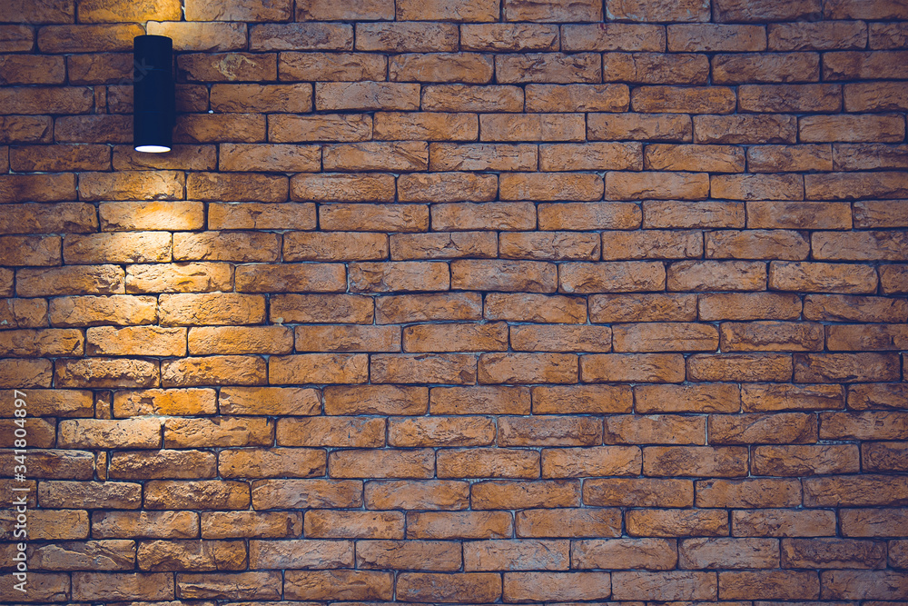 A section of a brown brick wall with an artificial light lamp. A section of a brown brick wall with an artificial light lamp.