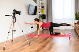 Concept of video of training, yoga video tutorial. A young woman practices yoga and records herself on camera. Online trainer, coach