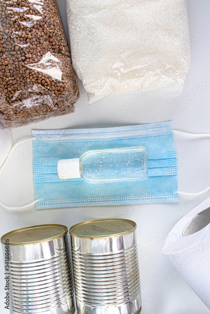 Food supplies during quarantine and self-isolation. Donation, food delivery. Sugar, buckwheat, canned food, toilet paper, medical face mask, antiseptic for hands and other surfaces, top view Food supplies during quarantine and self-isolation. Donation, food delivery. Sugar, buckwheat, canned food, toilet paper, medical face mask, antiseptic for hands and other surfaces, top view