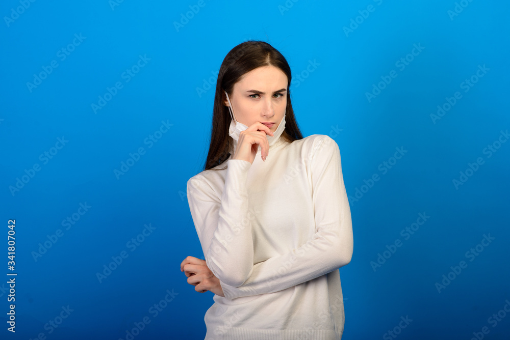 Portrait of a girl in a medical mask, which puts on a rubber glove. Blue background. Copy space. Portrait of a girl in a medical mask, which puts on a rubber glove. Blue background. Copy space.