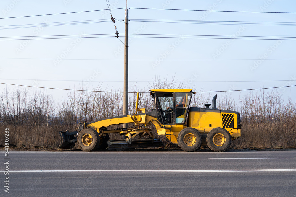Grader is working on road construction. Grader industrial machine on construction of new roads. Heavy duty machinery working on highway. Construction equipment. Compaction of the road. Grader is working on road construction. Grader industrial machine on construction of new roads. Heavy duty machinery working on highway. Construction equipment. Compaction of the road.