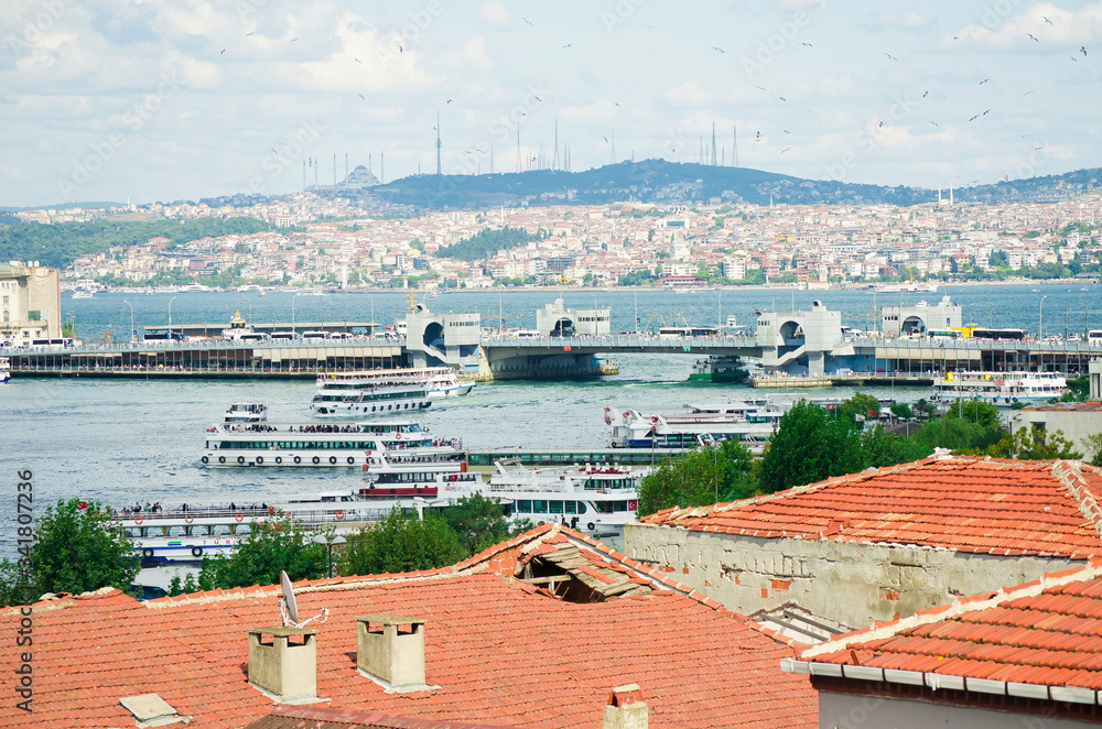 Touristic boats in Golden Horn bay and view on Galata bridge and Suleymaniye mosque. View of old city, mosque, red tile roofs and green trees.  Popular destination. Turkey, Istanbul