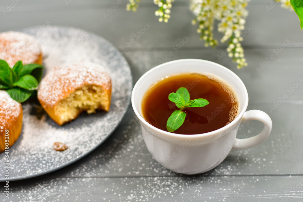 Composition with a cup of tea, cupcakes and white cherry flowers on a wooden background. Composition with a cup of tea, cupcakes and white cherry flowers on a wooden background.