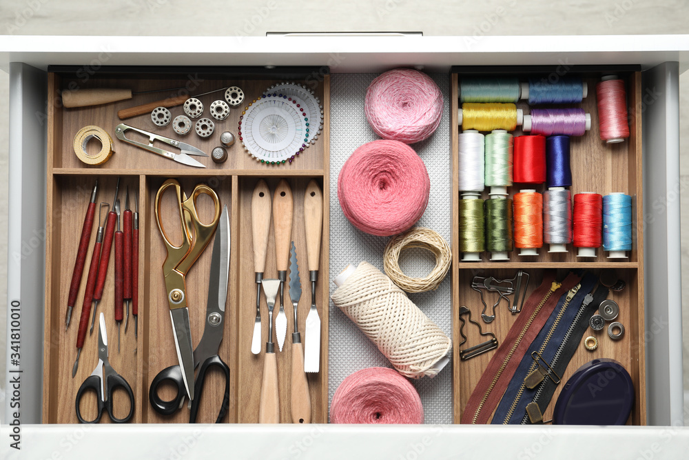 Naklejka premium Sewing accessories in open desk drawer, top view