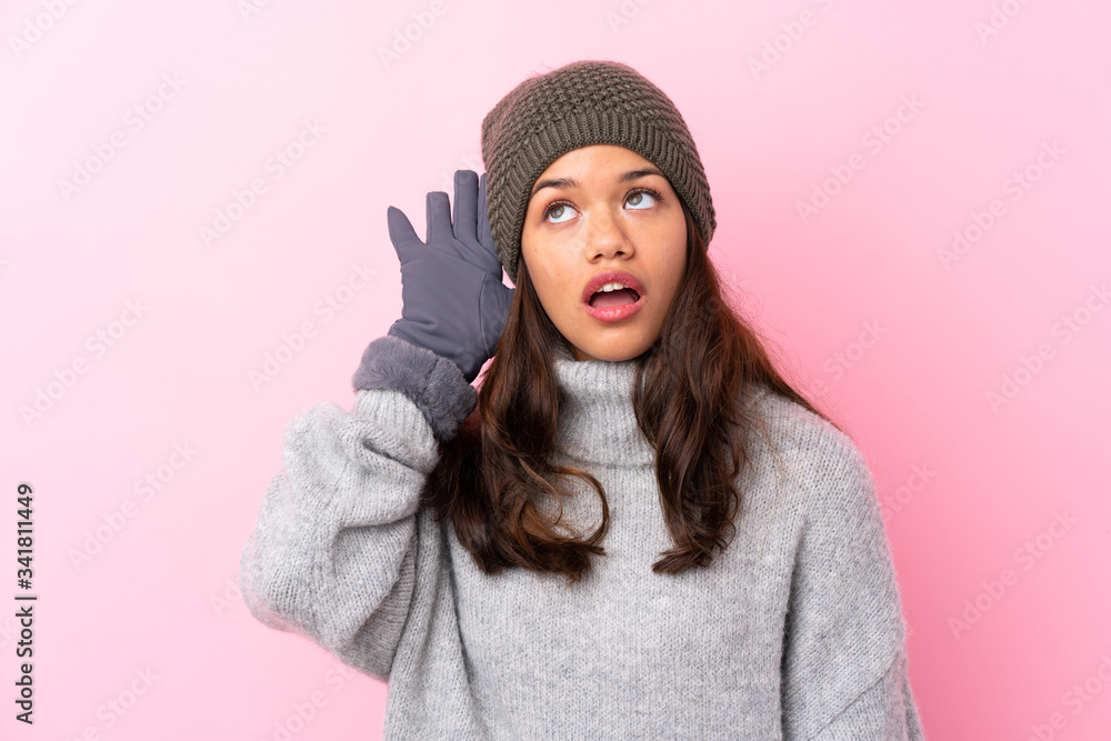 Young Colombian girl with winter hat over isolated pink wall listening something Young Colombian girl with winter hat over isolated pink wall listening something