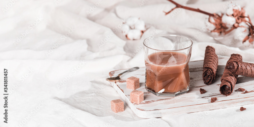 A cup of cold espresso coffee with cream and waffle tubule with chocolate filling in bed. Sweet breakfast, copy space for your text A cup of cold espresso coffee with cream and waffle tubule with chocolate filling in bed. Sweet breakfast, copy space for your text