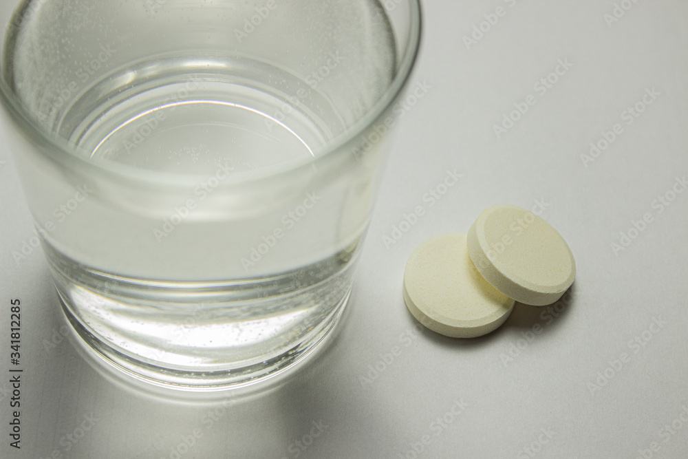a glass of water on the table and tablets