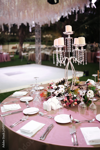 International Wedding outdoor celebration EVENING party under palm trees. Served tables on green area in hotel. Landyard. Beige and pink colors. Close-up and wide angle. photo