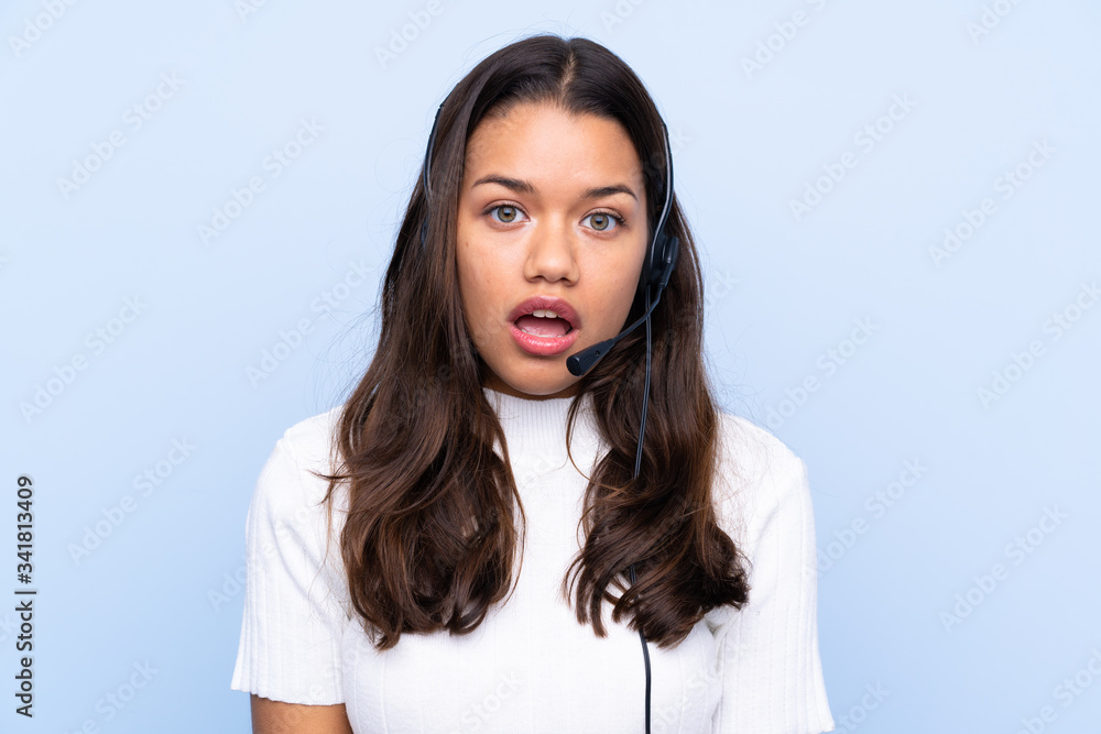 Young telemarketer Colombian woman over isolated blue background with surprise facial expression Young telemarketer Colombian woman over isolated blue background with surprise facial expression