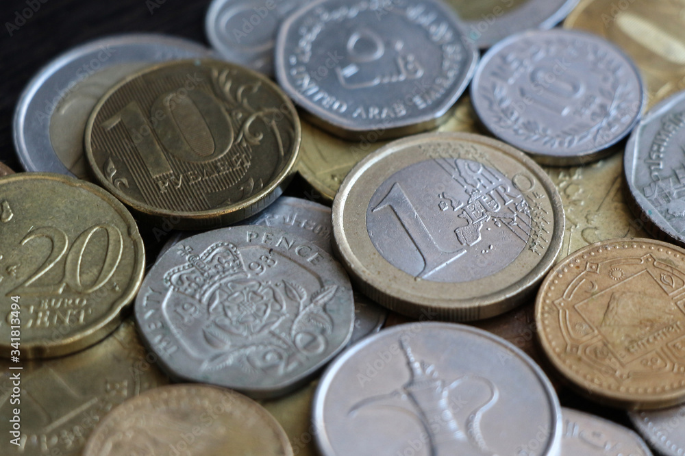 A collection of coins of different countries lies on a wooden table next to each other. Focus on one euro coin of European Union. Theme of the world economy. A collection of coins of different countries lies on a wooden table next to each other. Focus on one euro coin of European Union. Theme of the world economy.