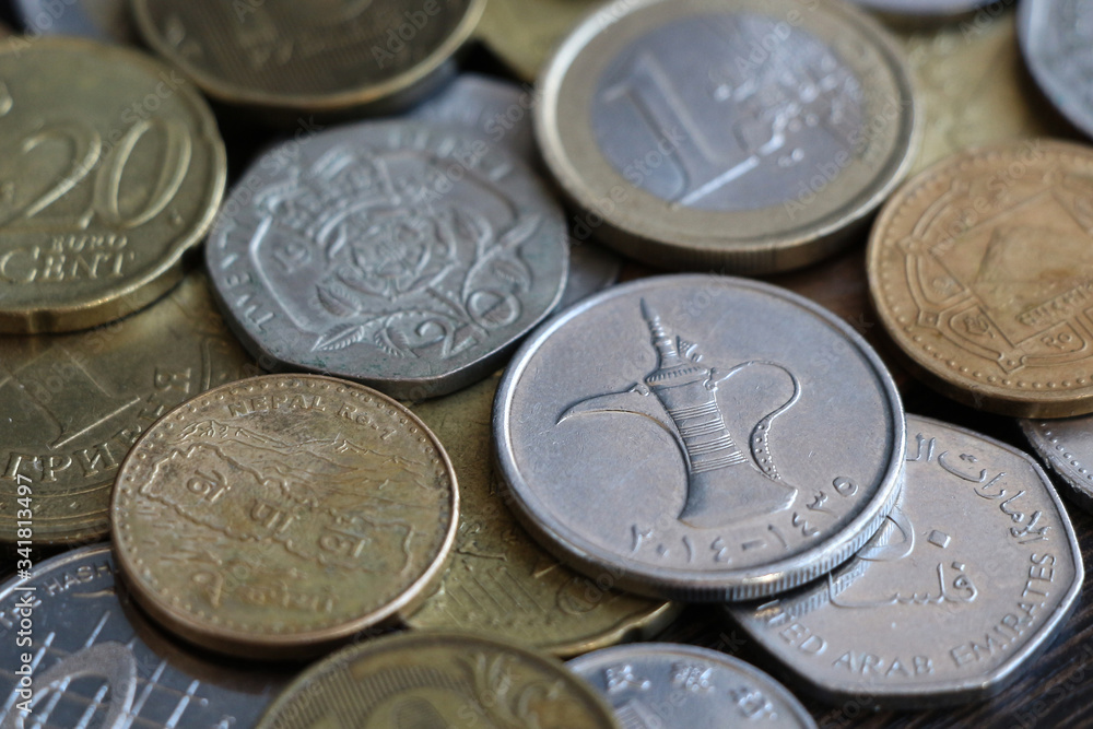 A collection of coins of different countries lies on a wooden table next to each other. Focus on one Dirham Coin of United Arab Emirates. Theme of the world economy. A collection of coins of different countries lies on a wooden table next to each other. Focus on one Dirham Coin of United Arab Emirates. Theme of the world economy.