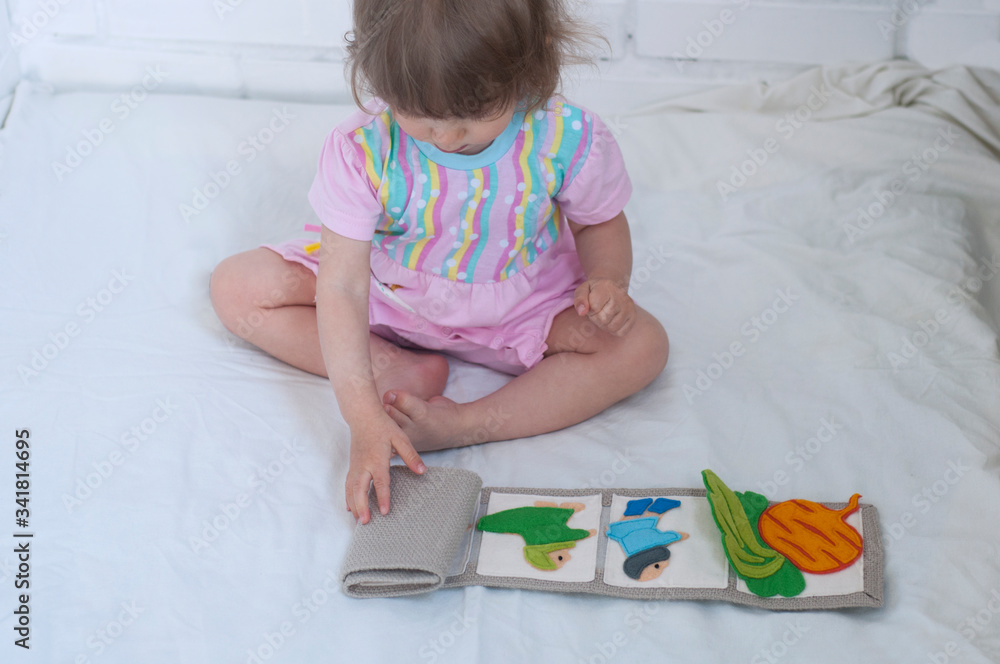 Baby playing with handmade textile book. Child opening an ineractive book with funny felt toys. Early development. Colourful educational toy. Baby playing with handmade textile book. Child opening an ineractive book with funny felt toys. Early development. Colourful educational toy.