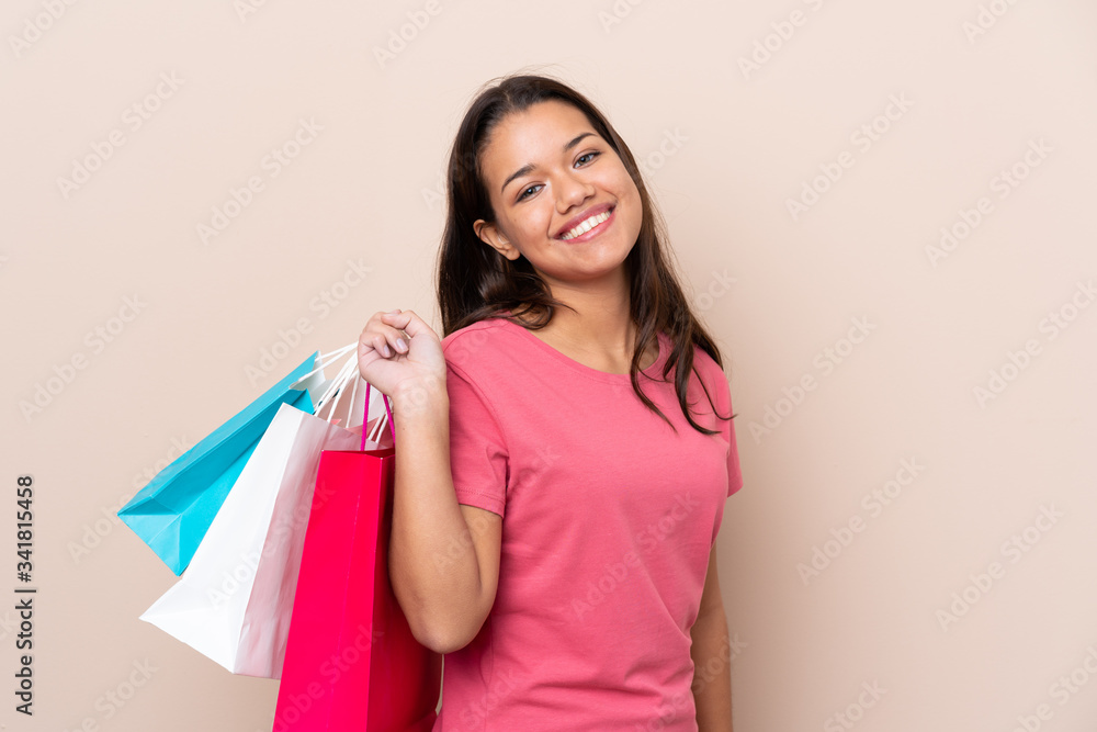 Young Colombian girl with shopping bag over isolated background holding shopping bags and smiling Young Colombian girl with shopping bag over isolated background holding shopping bags and smiling