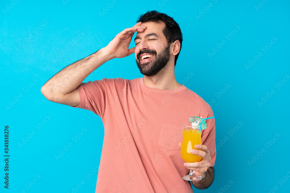Young man over holding a cocktail over isolated blue background smiling a lot Young man over holding a cocktail over isolated blue background smiling a lot