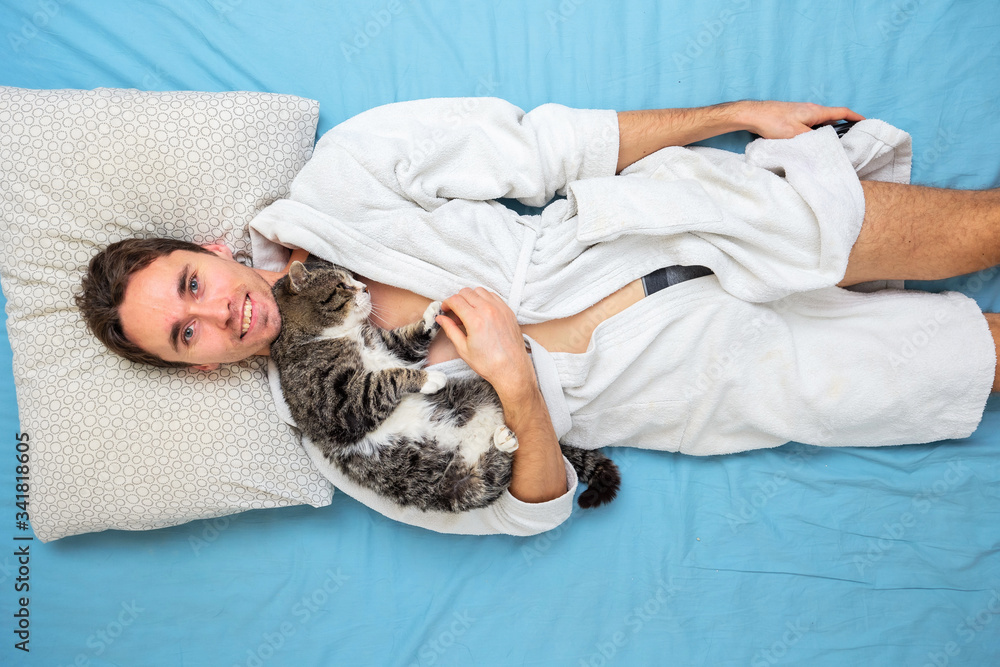 Smiling man with cat lying in bed Smiling man with cat lying in bed