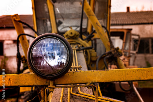Headlight and front part of an old abandoned broken road construction machine