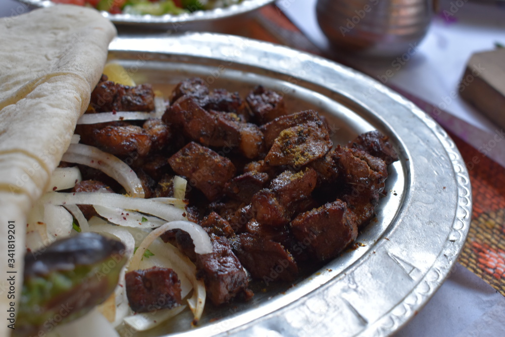 Close up view of liver kebab in a plate served with onions and special bread
