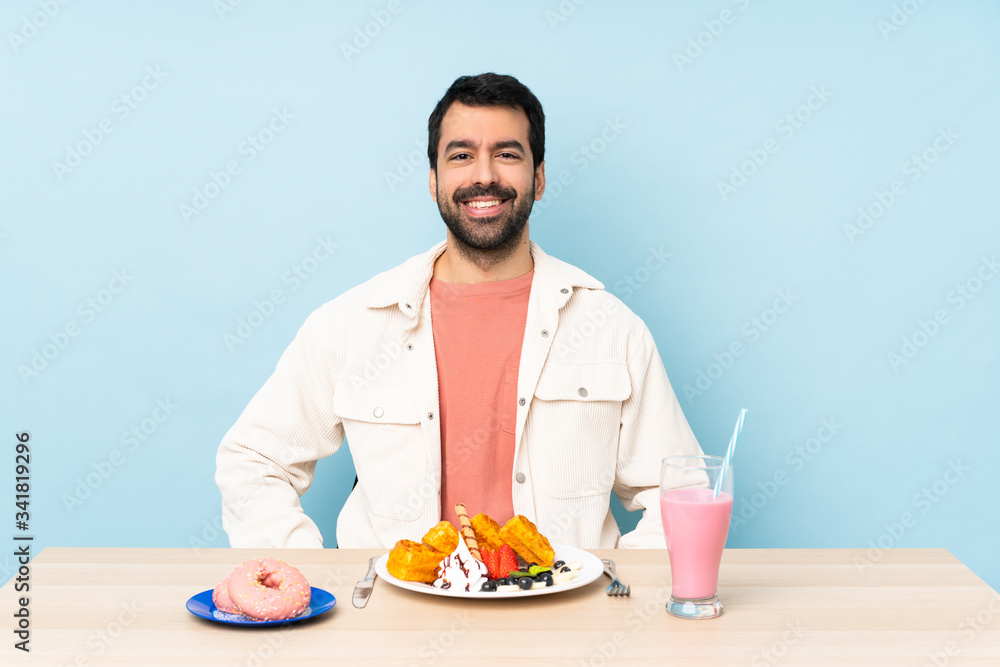 Man at a table having breakfast waffles and a milkshake laughing Man at a table having breakfast waffles and a milkshake laughing
