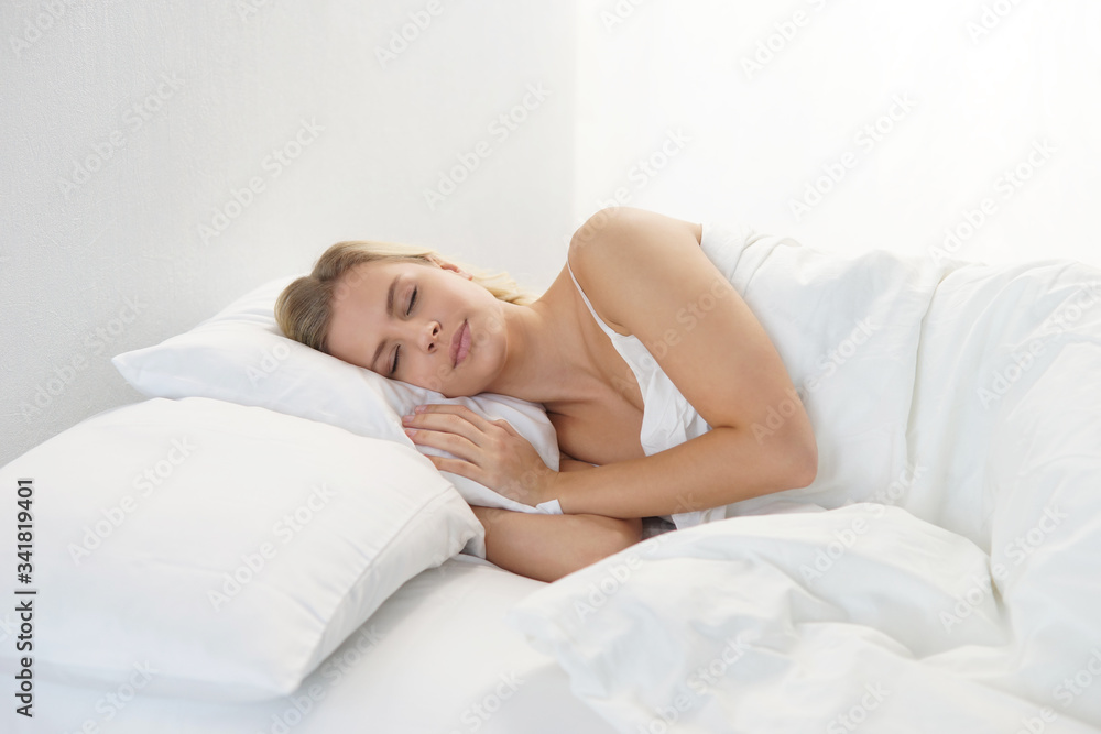 Young woman lying in the bed. Beautiful blond sleeping girl. Morning in the bedroom, daylight from the window. Health and rest. Young woman lying in the bed. Beautiful blond sleeping girl. Morning in the bedroom, daylight from the window. Health and rest.