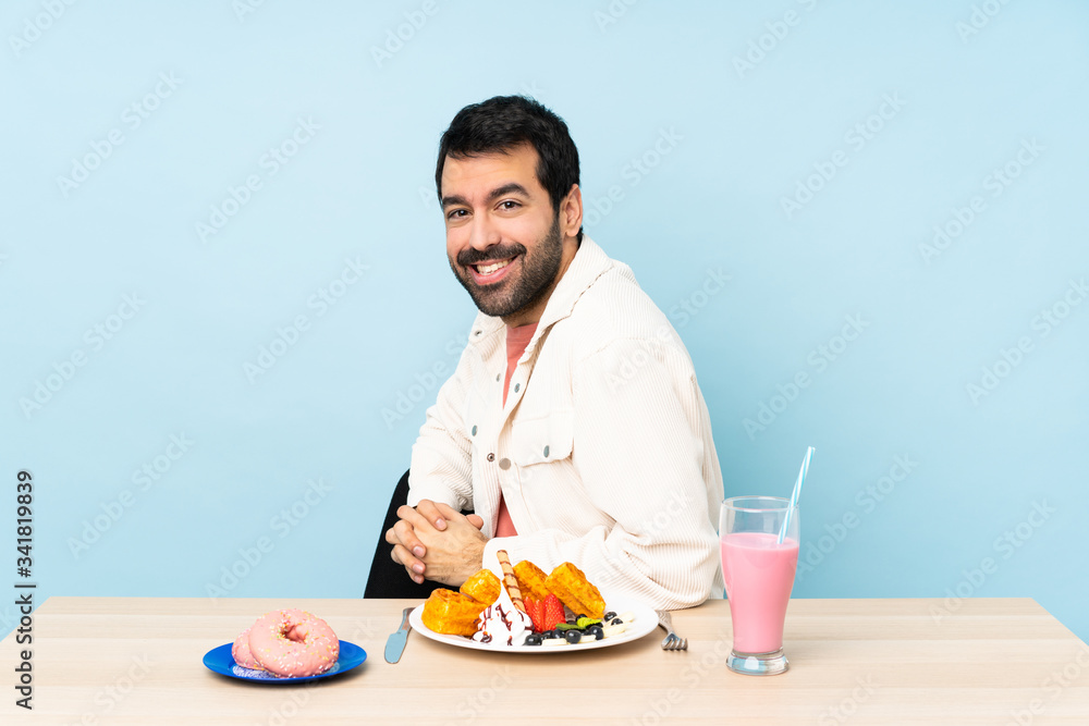 Man at a table having breakfast waffles and a milkshake with arms crossed and looking forward Man at a table having breakfast waffles and a milkshake with arms crossed and looking forward