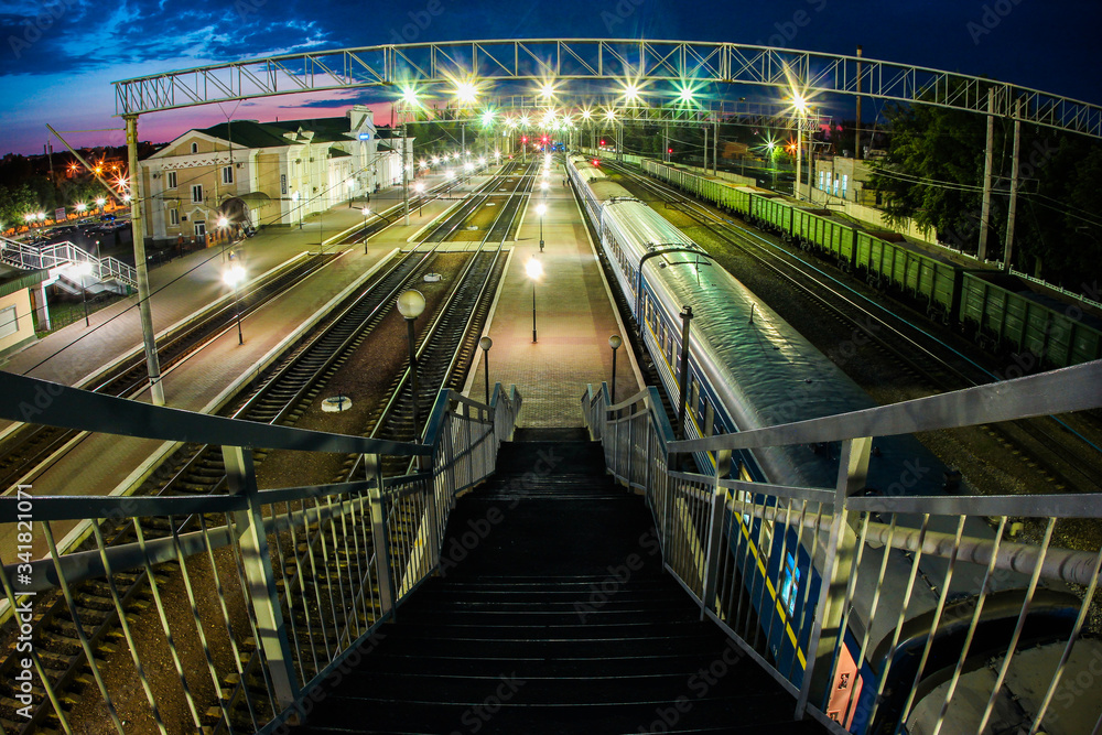 The train station at night and the train is waiting for departure. Passenger cars
