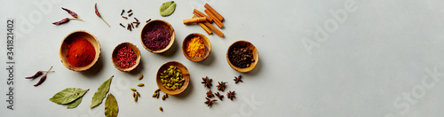 Various colorful spices in wood bowls on concrete background. Top view with copy space. Different Pepper, turmeric, paprika, rosemary, chilly, cardamom, cinnamon, anise, cloves.