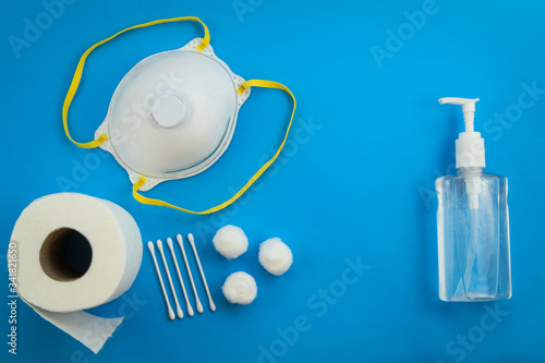 Health care safe cleaning kit for Coronavirus Covid-19 prevention concept. Flat lay on blue with mask, hand sanitizer, gloves, toilet paper, cotton.