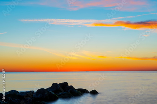 Amazing cloudy spring sunset over deep blue ocean and endless horizon, with boulders in the foreground island of Gotland in the Baltic Sea, Sweden © It4All