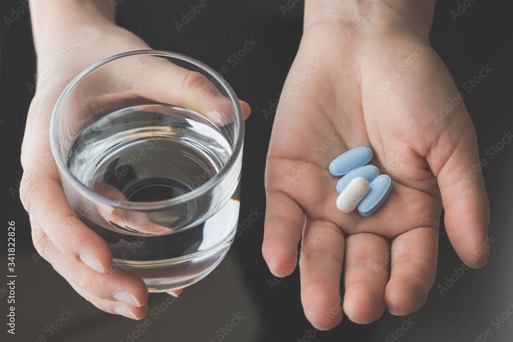 hand holding pills and glass of water hand holding pills and glass of water