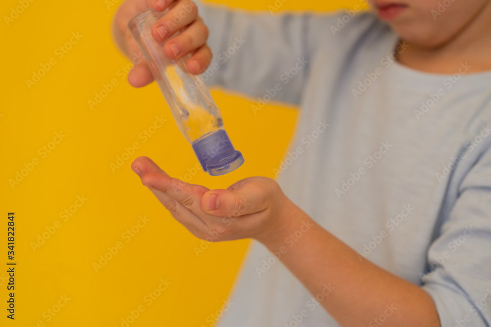 children’s hand holds bottle of transparent hand sanitizer gel on yellow background. Hand hygiene. kids hygiene. Bacteria and virus protection children’s hand holds bottle of transparent hand sanitizer gel on yellow background. Hand hygiene. kids hygiene. Bacteria and virus protection