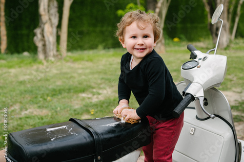 Young kid pretending to wash a typical Italian motorcycle. Family activity