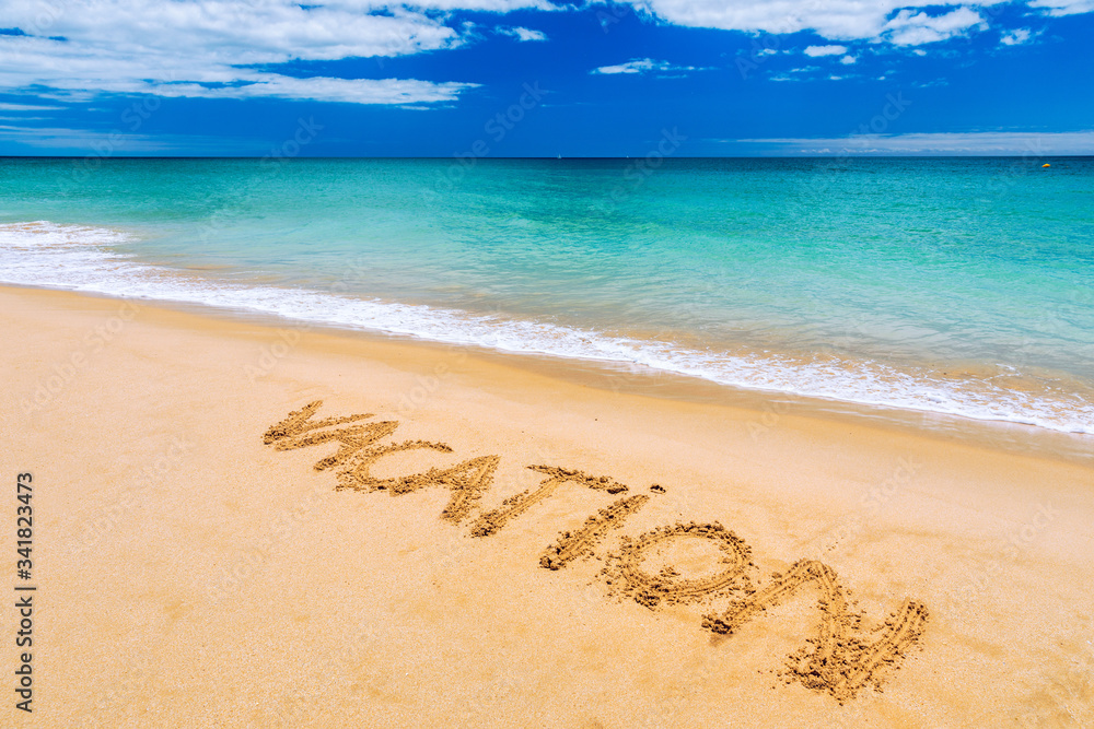 Fototapeta premium Vacation text on a beach. Vacation written in a sandy tropical beach. 