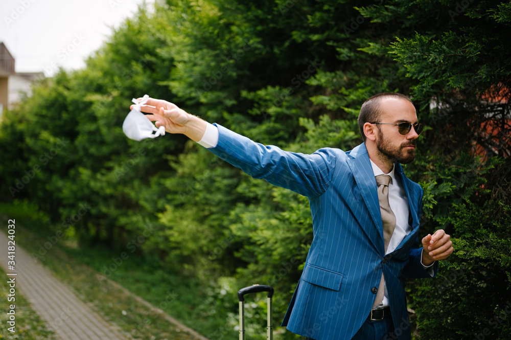 Young businessman taking off his protection mask on alleyway. End of quarantine Young businessman taking off his protection mask on alleyway. End of quarantine