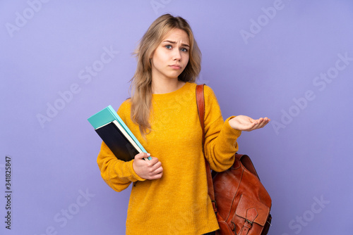 Teenager Russian student girl isolated on purple background unhappy for not understand something